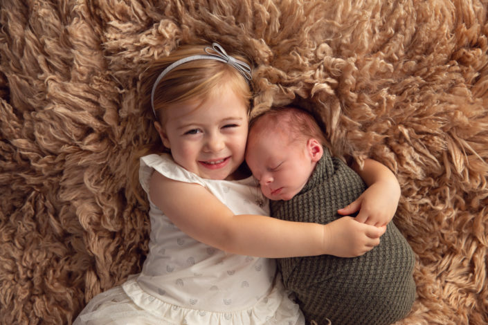newborn and sister hugging