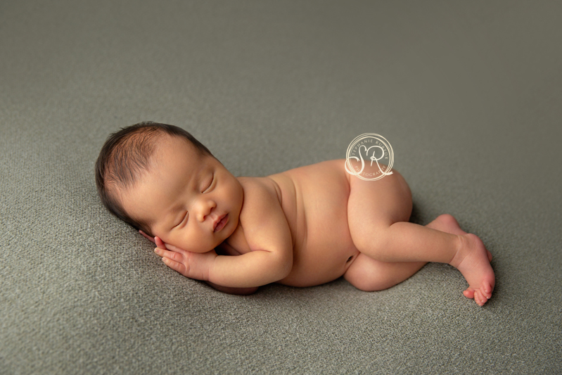 Newborn baby boy asleep on blanket in Fort Worth photo studio.