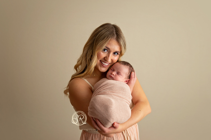 A beautiful new mom holding her newborn daughter in Saginaw photo studio.