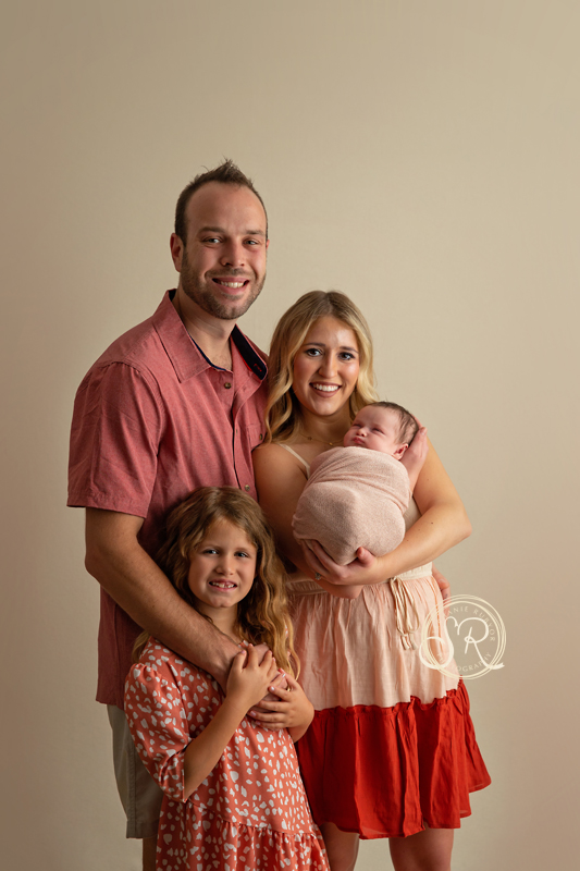 A beautiful new mom and dad holding their newborn daughter in Saginaw photo studio.