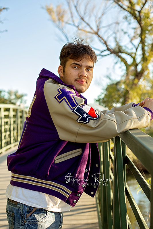 A senior guy with his lettermans jacket on at Marine Creek Lake in Fort Worth, Texas. 