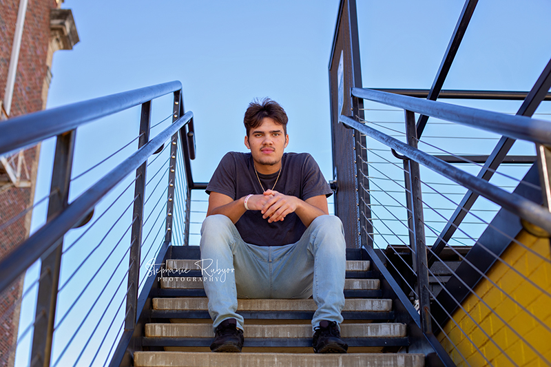 Weston sitting on a rooftop in downtown Fort Worth for his senior photo shoot.