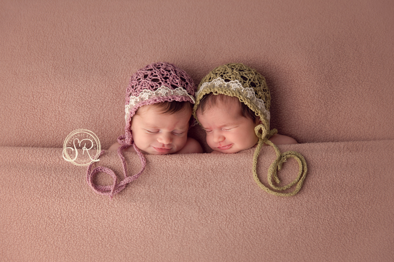 Newborn twin girls smiling at each other during their photo session in Fort Worth.