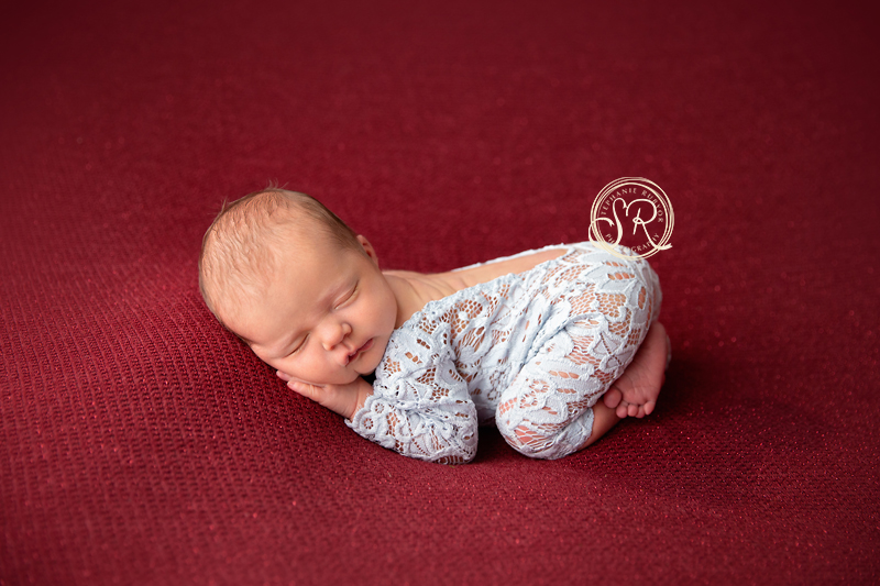 Baby girl in blue lace outfit sleeping at her newborn photo session. 