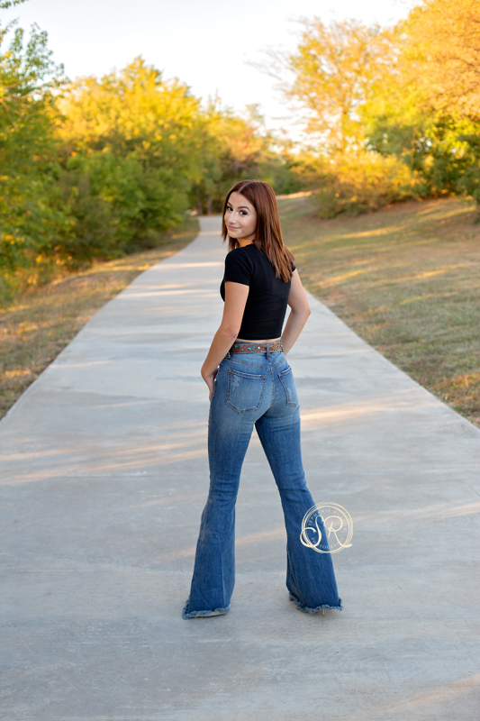 Senior photo shoot on the sidewalk with her looking over her shoulder at me at Marine Creek Lake. 