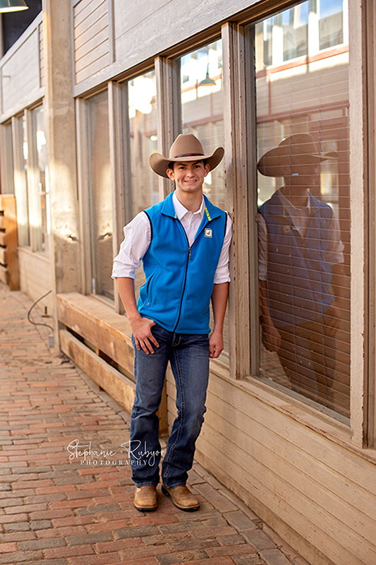 Fort Worth Stockyards photo session in one of the many alleys with a senior guy posing by a window.
