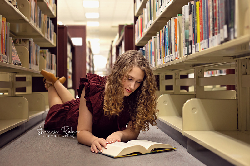 Senior girl reading a book for her photo session at the public library in Fort Worth, Texas.
