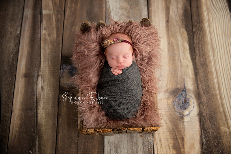 Baby girl wrapped in gray sleeping in a wooden crib in Saginaw. 