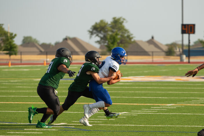 High school football player carrying the ball downfield at local high school football game in Fort Worth, Texas.