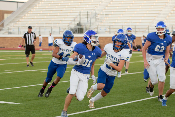 High school football player carrying the ball downfield at local high school football game in Fort Worth, Texas.