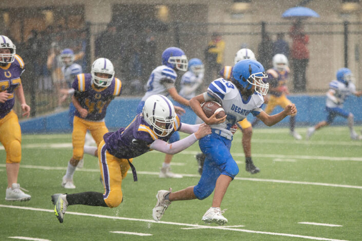 High school football player carrying the ball downfield at local high school football game in Fort Worth, Texas.