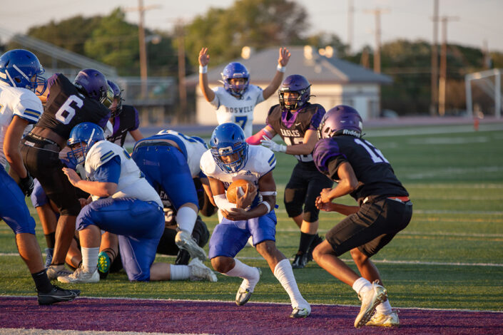 High school football player carrying the ball downfield at local high school football game in Fort Worth, Texas.