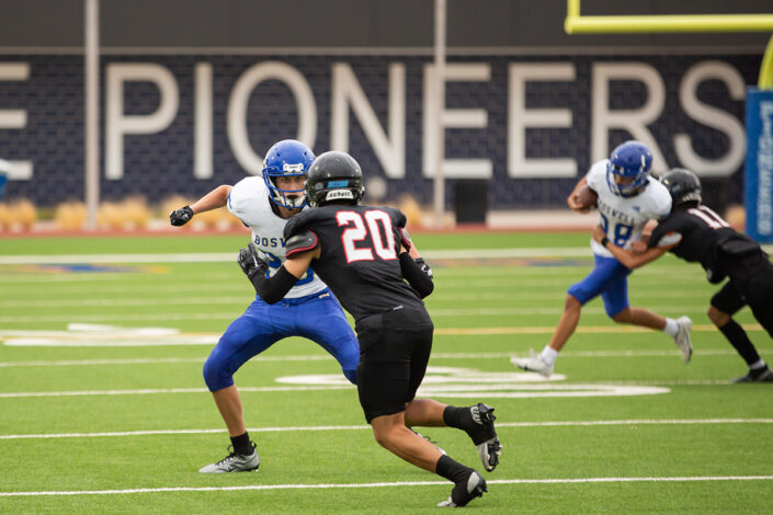 High school football player carrying the ball downfield at local high school football game in Fort Worth, Texas.