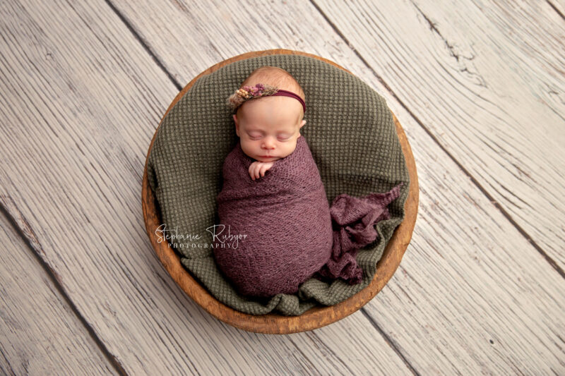 Wrapped newborn baby sleeping in bowl at a newborn photo session in Fort Worth, Texas.