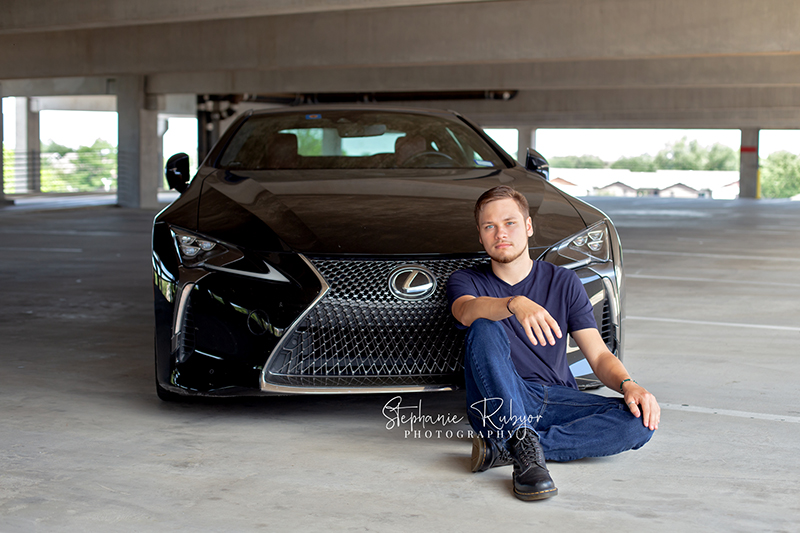 Senior boy posing with his car in a Fort Worth garage for his senior session.