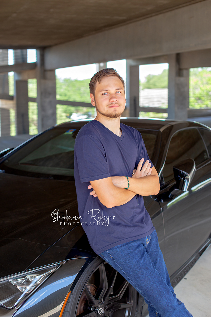 Senior boy posing with his car in a Fort Worth garage for his senior session. 