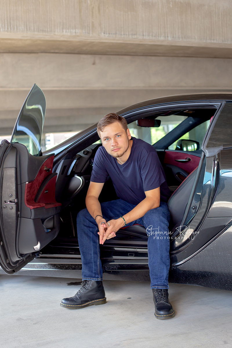 Senior boy posing with his car in a Fort Worth garage for his senior session. 