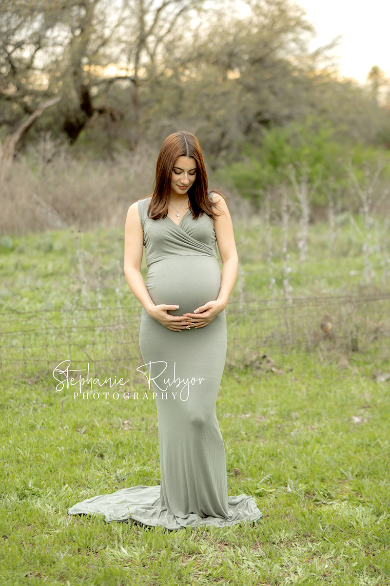 New mother to be posing in sage green maternity dress for maternity pictures at Eagle Mountain Park.