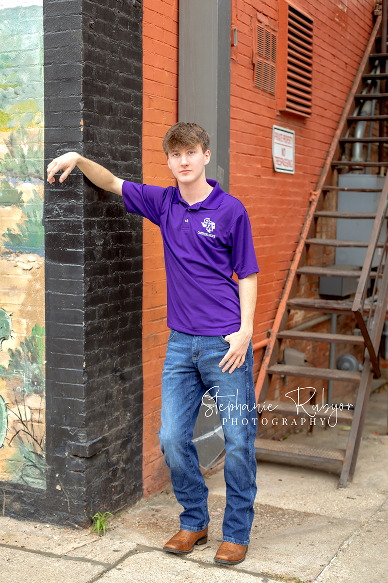 High school senior guy posing for senior portraits at the Stockyards in Fort Worth, Texas. 