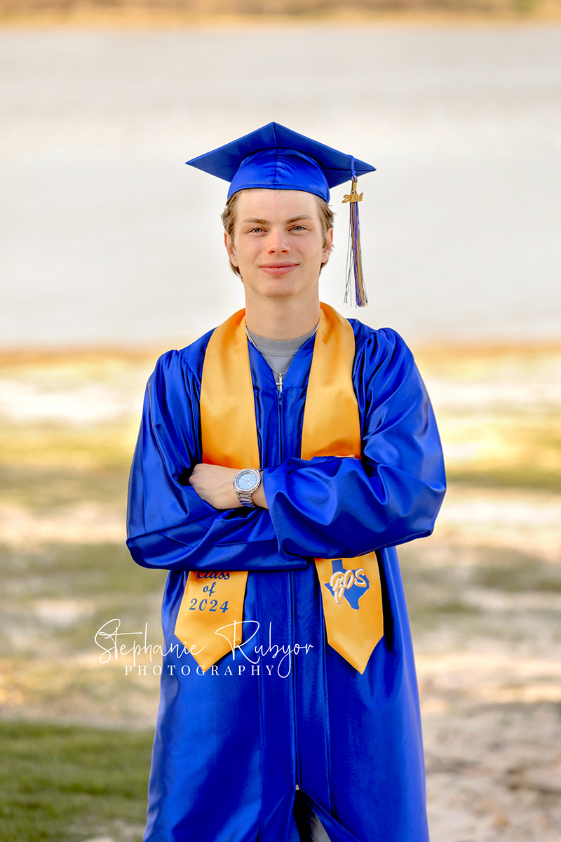 Senior boy posing in cap & gown at his photo session in Fort Worth.