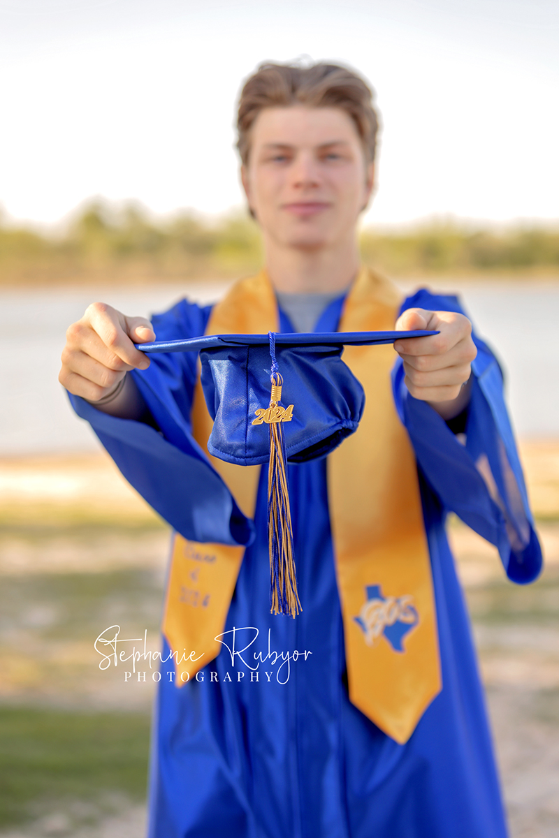 Senior boy posing in cap & gown at his photo session in Fort Worth.
