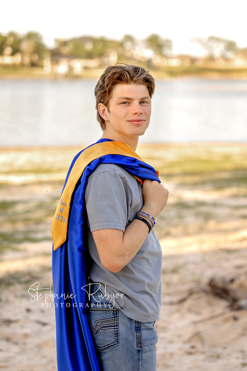 Senior boy posing in cap & gown at his photo session in Fort Worth.