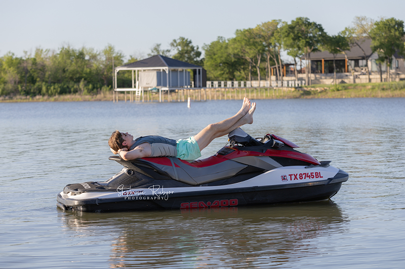 High School senior boy jet skiing on Eagle Mountain Lake for his senior pictures session. 