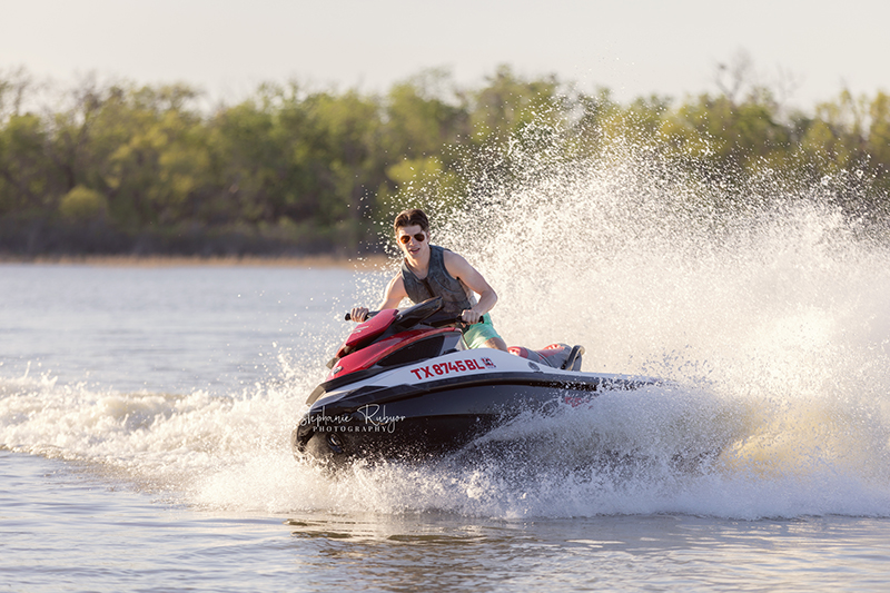 High School senior boy jet skiing on Eagle Mountain Lake for his senior pictures session. 