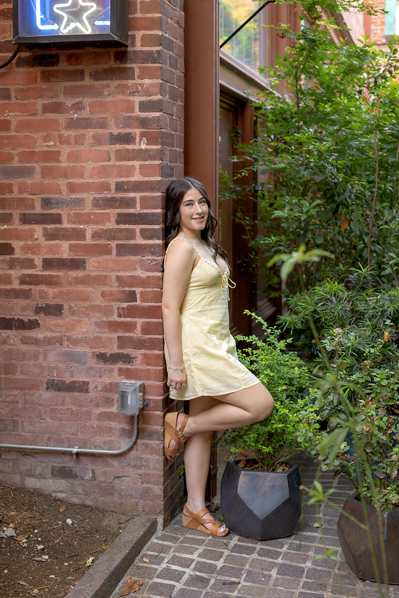 Senior gal posing for pictures in a yellow sundress at Sundance Square downtown Fort Worth. 