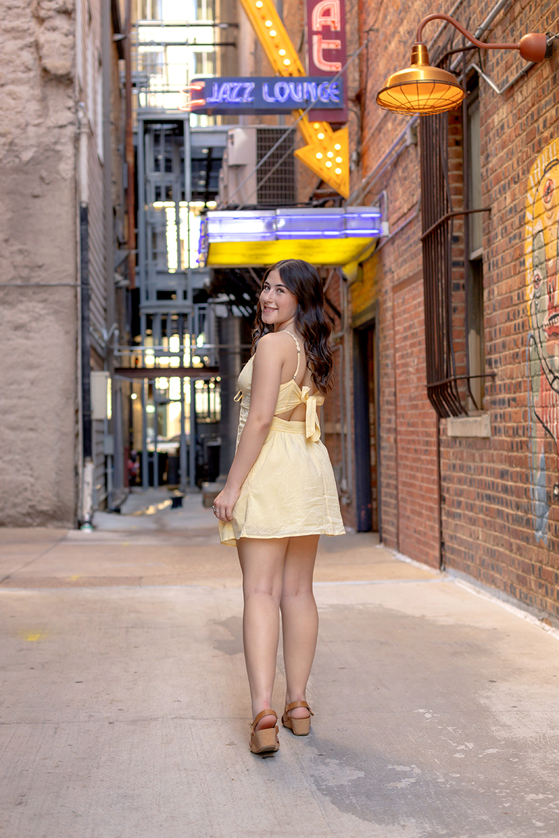 Senior gal posing for pictures in a yellow sundress at Sundance Square downtown Fort Worth. 