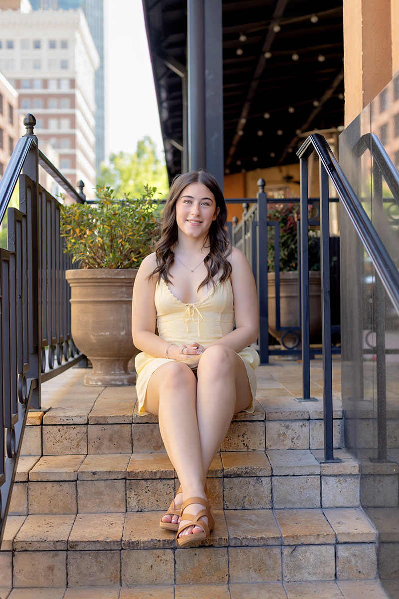 Senior gal posing for pictures in a yellow sundress at Sundance Square downtown Fort Worth. 
