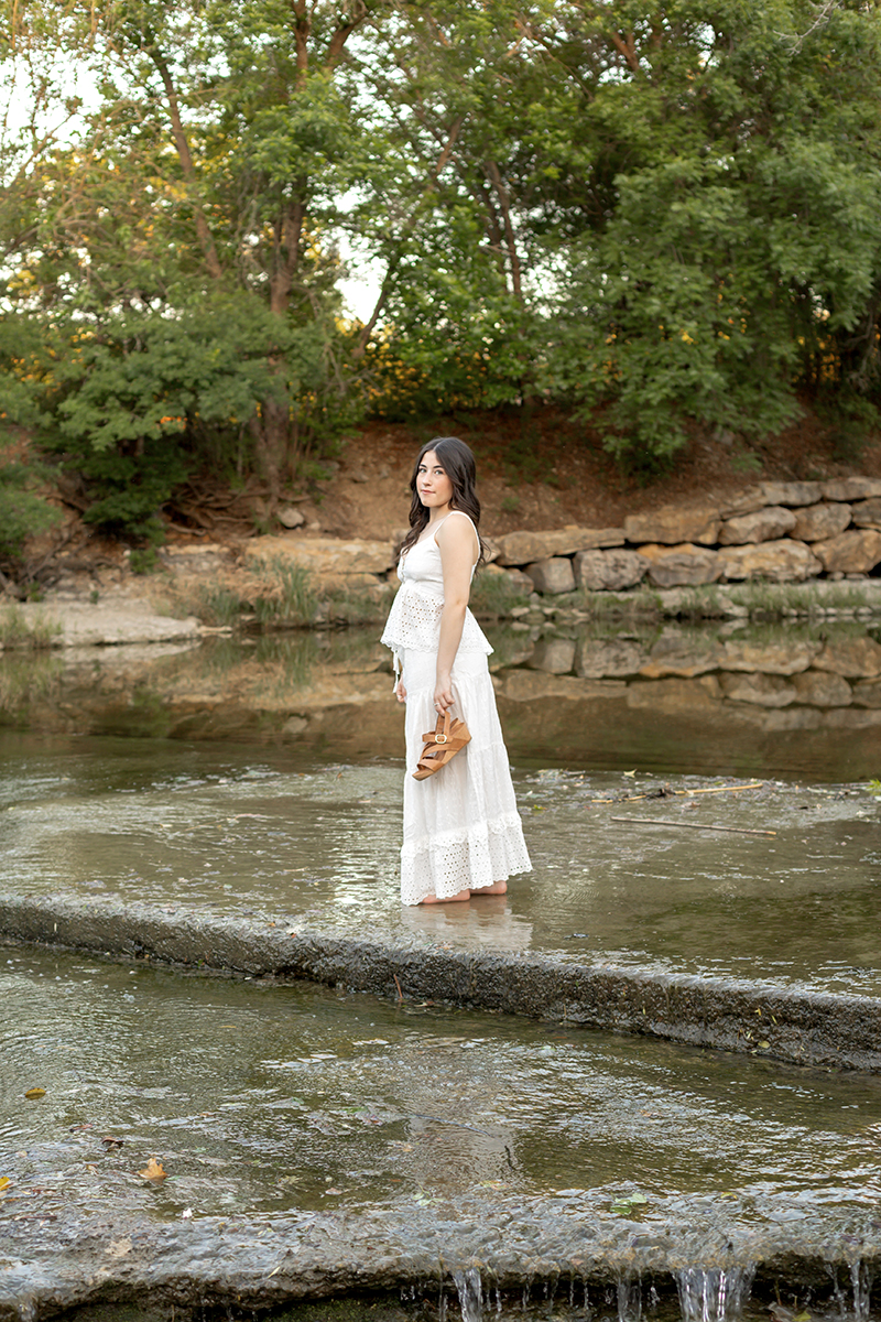 High school senior standing in Airfield Falls in Fort worth for her senior photo session. 